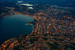 Aerial Cityscape Prints: High angle aerial drone shot view Lugano by lake with city street lights after sunset in Switzerland