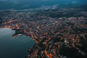 Aerial Cityscape Prints: High angle aerial drone shot view Lugano by lake with city street lights after sunset in Switzerland