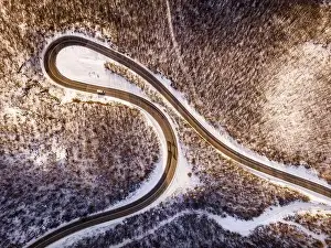 High angle aerial view drone image on the curved serpentine road trough the trees