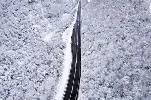 Winter Mountain Prints: High angle aerial view drone image on the road trough the trees