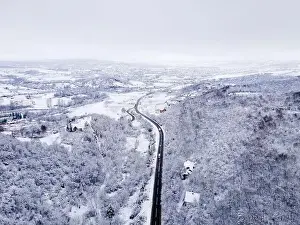Winter Mountain Prints: High angle aerial view drone image on the road trough the trees
