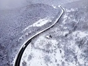 Winter Mountain Prints: High angle aerial view drone image on the road trough the trees