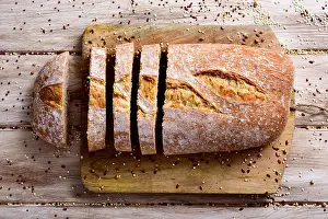 High Angle Shot Prints: high-angle shot of a loaf of spelt bread cut in some slices on a chopping board