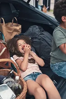 High angle view of girl eating apple by brother in car trunk