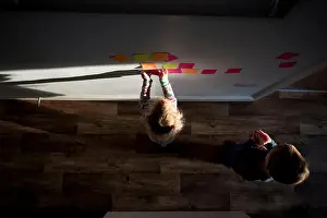 Sticking Prints: High angle view of siblings sticking adhesive notes on wall at home