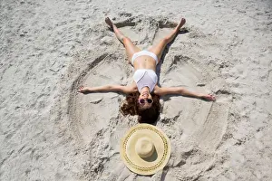 Toothy Smile Prints: High angle view of woman making sand angel at beach on sunny day