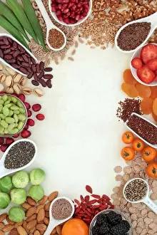 High fibre health food background border of fresh vegetables, fruit, grains, whole wheat pasta, cereals, nuts & seeds on parchment paper