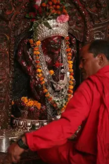 Puja Prints: High priest sits in front of the statue of the goddess Kali in the main sanctuary in the Dakshinkali Temple near