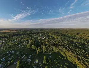 High View from the height of a flying drone, a small village with houses and cottages, green fields on a summer day