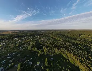 High View from the height of a flying drone, a small village with houses and cottages, green fields on a summer day