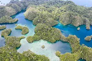 Equator Prints: Highly eroded limestone islands and coral reefs lie amid the waters of Raja Ampat