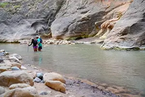 Natural World Prints: Two hikers stand in shallow river water surrounded by canyon walls