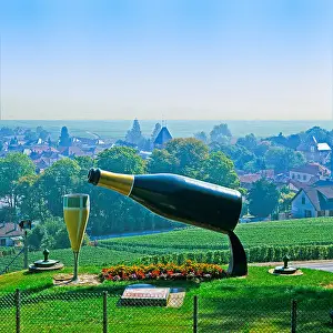 Hilltop giant bottle of Champagne pouring into huge glass