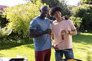 Two Men Prints: Hispanic and African American male friends grilling corn at backyard grill while holding drinks