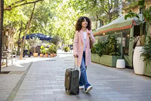 Toothy Smile Prints: A Hispanic woman with curly hair walks down a sunlit city street