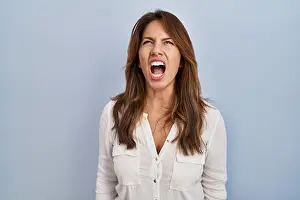 Hispanic woman standing over isolated background angry and mad screaming frustrated and furious