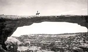 Ridge Prints: Historical image. Trust. Dan Perkins of the US Geological Survey standing on his horse Cap on top of Owachomo Bridge