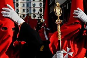 Malaga Prints: The Holy Week participants hold their traditional robe while walking against the wind during the Easter in Malaga