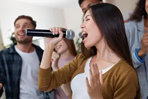 Guys Prints: Home party. Young beautiful asian girl holding microphone