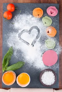 Homemade multicolor ravioli with vegetables on a slate blackboard