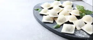 Dumpling Prints: Homemade uncooked ravioli and basil on grey table
