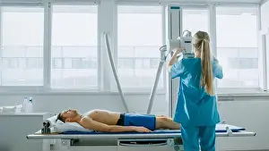 Ward Prints: In the Hospital, Man Lying on a Bed Waiting for X-Ray Machine to Scan His Leg for Injury