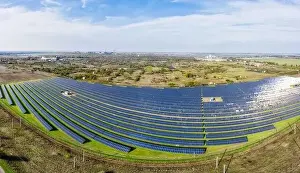 Huge solar power plant to use solar energy in a picturesque green field in Ukraine. Aerial panoramic drone shot