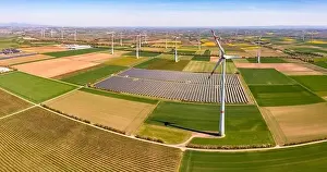 Agricultural Land Prints: Huge wind turbines between agricultural land and a solar park in a rural area from a drone view