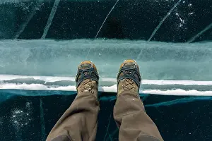 Caucasus Prints: Human legs in hiking boot in ice crampons on the texture Baikal ice