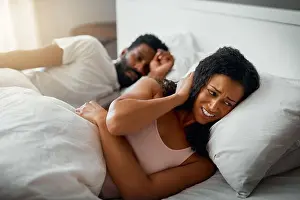 At Home Prints: I cant sleep like this. Cropped shot of a beautiful wife annoyed by her handsome husbands snoring in bed at home