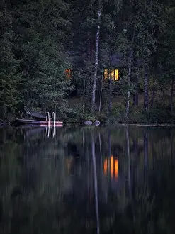 Midsummer Prints: Idyllic cottage view with cozy cottage and window ligth at tranquil summer night in Finland