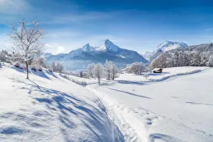Salzburg Prints: Idyllic winter wonderland scenery with trees and mountain tops in the Alps on a sunny day with blue sky and clouds