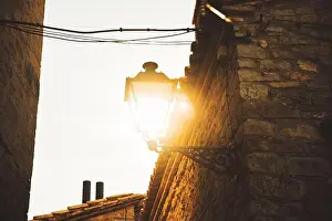 Connected Prints: Illuminated lamppost on a street in a village with stone houses