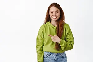 Sincere Prints: Image of cheerful redhead girl pointing finger left and smiles white teeth