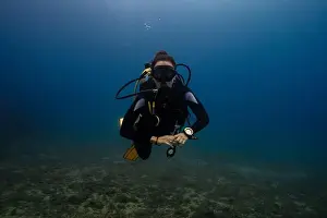 Wetsuit Prints: In this image, a female diver is depicted swimming underwater in a clear blue ocean environment