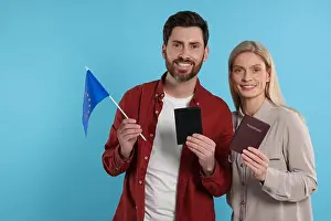 Citizenship Prints: Immigration. Happy couple with passports and flag of European Union on light blue background