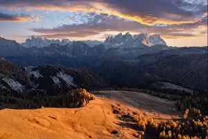 Incredible autumn view at Valfreda valley in Italian Dolomite Alps. Yellow grass, orange larches forest and snowy mountains peaks on background