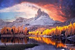 Incredible purple sunrise on Federa Lake in the Dolomite Apls. Autumn mountains landscape with Lago di Federa and bright orange larches