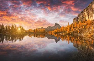 Incredible purple sunrise on Federa Lake in the Dolomite Apls. Autumn mountains landscape with Lago di Federa and bright orange larches