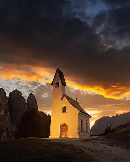 Incredible view on small iIlluminated chapel - Kapelle Ciapela on Gardena Pass, Italian Dolomites mountains. Colorful sunset in Dolomite Alps, Italy