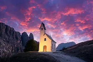 Incredible view on small iIlluminated chapel - Kapelle Ciapela on Gardena Pass, Italian Dolomites mountains. Colorful sunset in Dolomite Alps, Italy