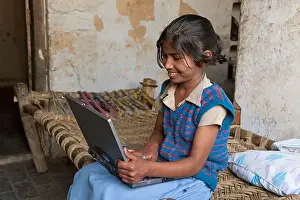 Pre Teen Prints: India, uttar Pradesh, Agra, Happy pre-teenage girl using laptop whilst sitting on bed
