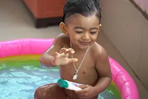 Inflatable Prints: indian baby boy enjoying bath in an inflatable pool with water splashing and float toys