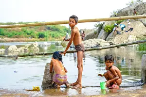 Siblings Prints: Three Indian children help each other wash in the river