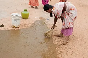Indian custom of a woman spreading watered down cow dung outside the front of her home. Andhra Pradesh, India