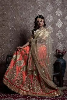 Sari Prints: Indian female model wearing an orange and beige lehemga and jewellry portraying an indian ethnic look