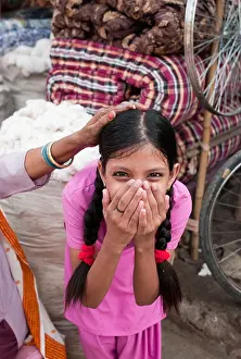 Shocked Prints: An Indian girl in a pink dress and pony tails smiling with her hands covering her mouth