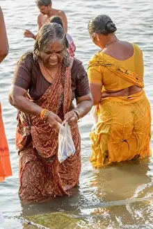 An Indian Hindu woman wearing a sari performs an early morning bathing ritual in the River Ganges in Varanasi