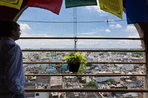 Pondering Prints: Indian man stands in the balcony on a fifth floor balcony overlooking the city of Hyderabad