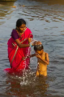Indian mother bathing his son on the waters of Tungabhadra river, Hampi, Karnataka, India